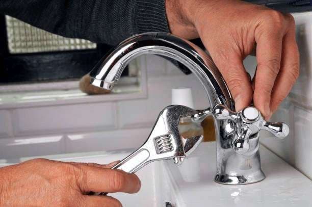 Plumber repairing a leaking bathroom tap in a Singapore flat